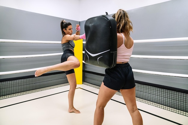 Female kickboxer practicing kicks with her partner in the ring