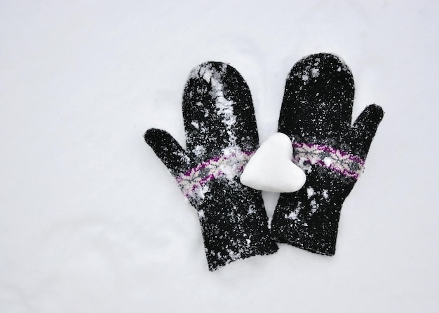 女性のニットのミトンと雪の心。コンセプトが大好きです。バレンタインデーの背景。