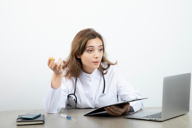 Female laboratory researcher sitting at the desk with clipboard and laptop . High quality photo