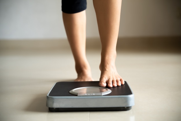 Photo female leg stepping on weigh scales. healthy lifestyle, food and sport concept.