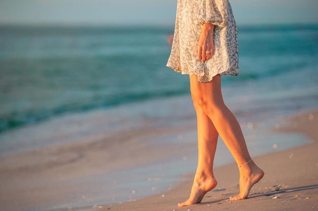 Photo female legs on the beach closeup woman in dress walking on the beach