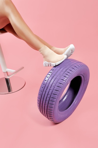 Female legs in beige sock sneakers leaning on car tire