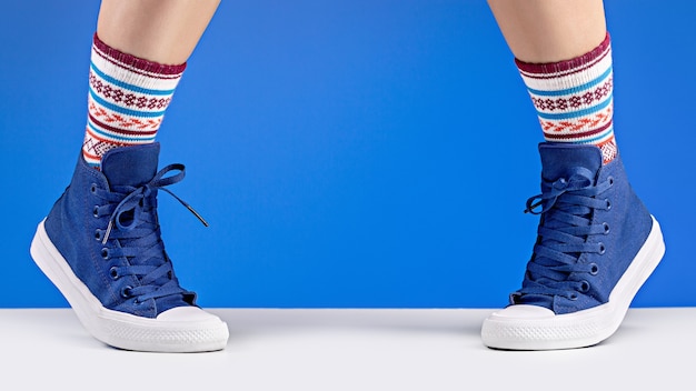 Photo female legs in blue sneakers and cozy socks