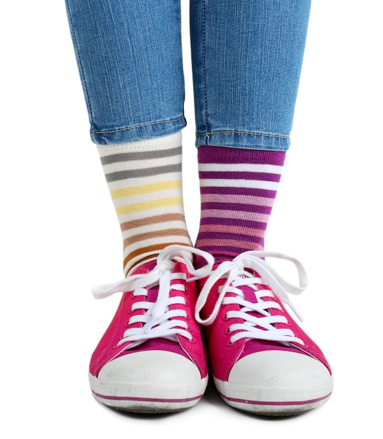 Female legs in colorful socks and sneakers isolated on white