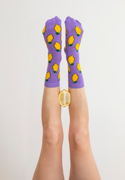 Gambe femminili in calzini colorati con limoni isolati su sfondo bianco