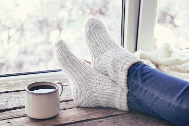 Female legs and hot drink on windowsill