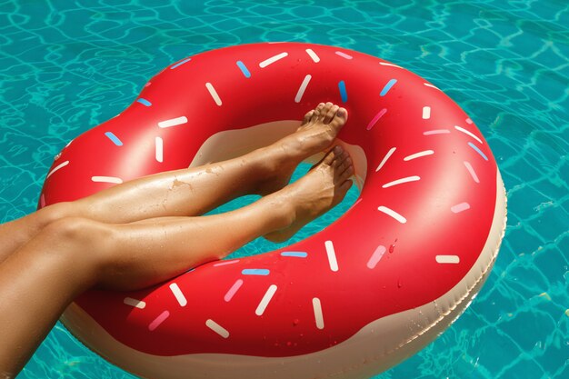 Female legs and inflatable swim ring in shape of donut