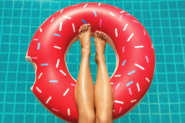 Female legs and inflatable swim ring in shape of donut