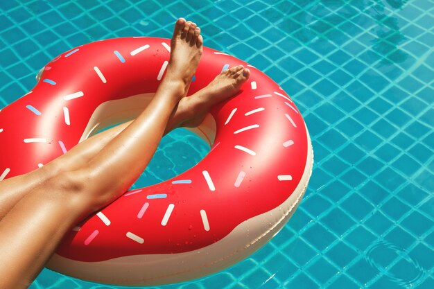 Female legs and inflatable swim ring in shape of donut