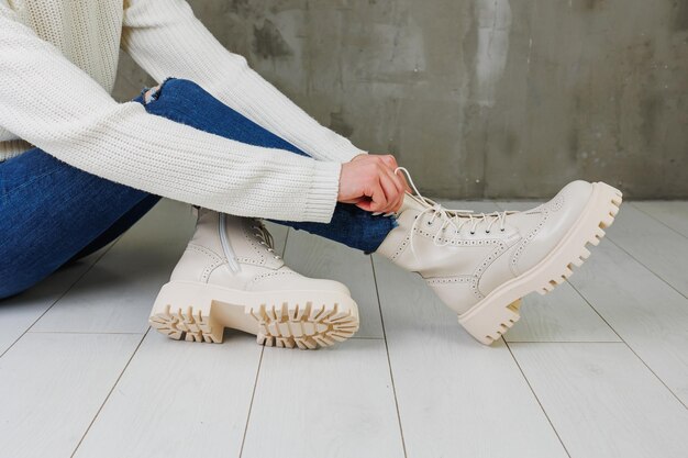 Female legs in jeans and white leather boots made of natural leather A collection of women's spring modern shoes