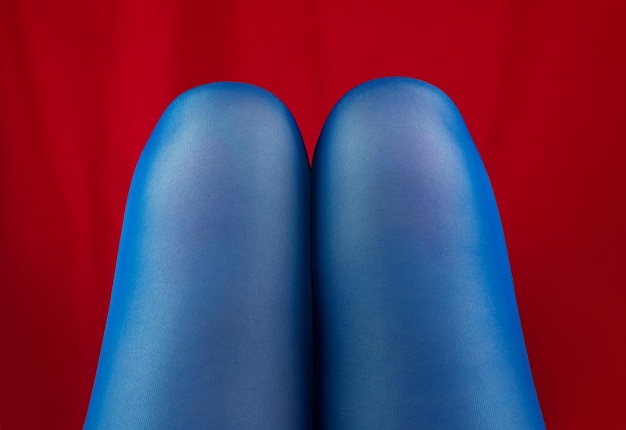 Photo female legs knees in blue tights on red fabric spring autumn fashion body positive concept