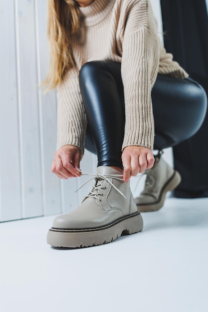 Female legs in leather beige autumn boots A girl stands in a store and measures shoes