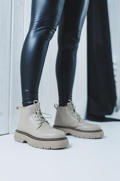 Female legs in leather beige autumn boots A girl stands in a store and measures shoes