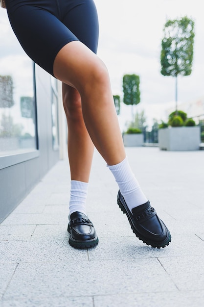 Female legs in leather shoes white socks with and black moccasins black shorts fashion details