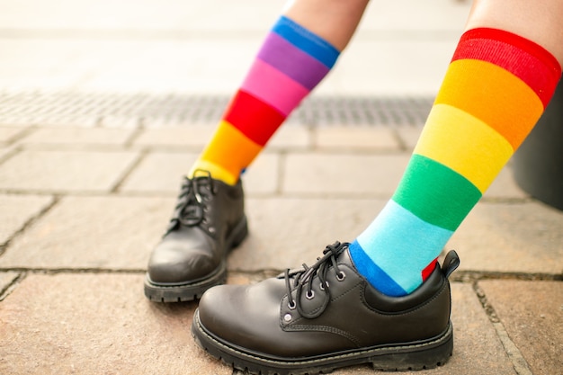 Female legs in lgbt rainbow socks wearing male boots