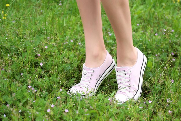 Female legs in pink sneakers on green grass