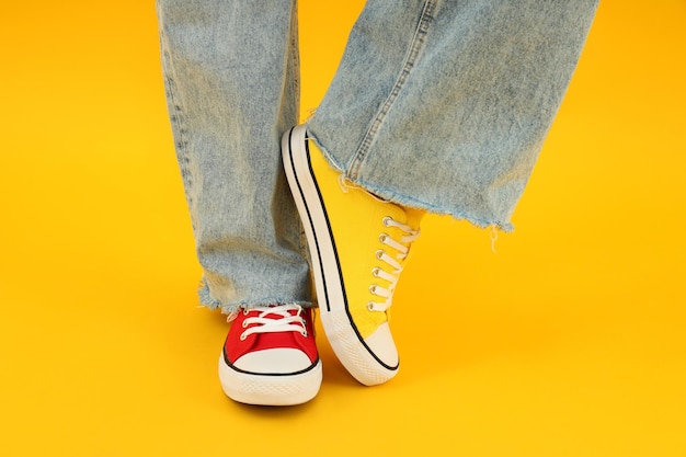 Female legs in red and yellow sneakers on yellow background