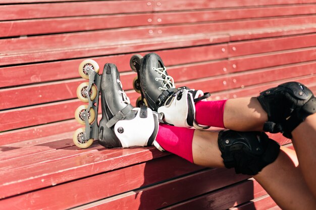 Female legs in roller skates on red wooden boards outdoors