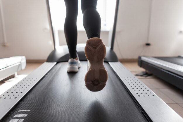 Female legs in sports shoes in gym.