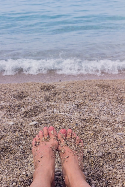 女性の足が海の水のビーチに立つ