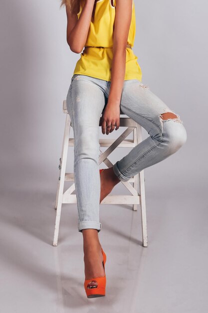 Female legs in stylish blue jeans and orange boots on grey background