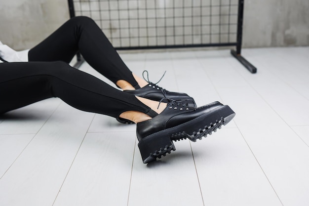 Female legs in trendy black leggings and loafers laces on leather shoes details of a stylish autumn fashion look