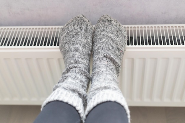 female legs in warm knitted socks on the radiator