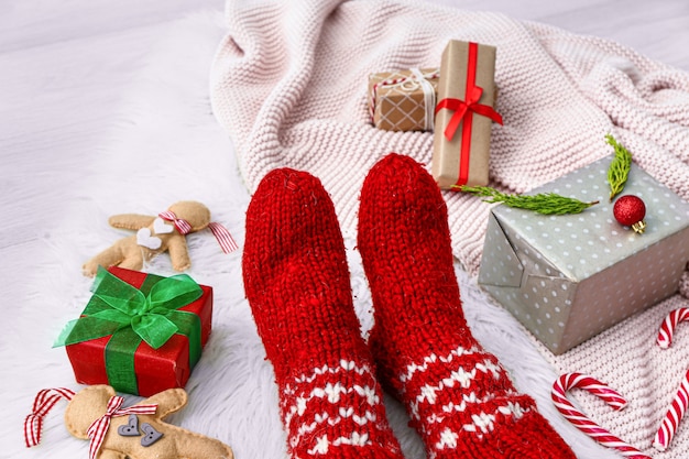 Female legs in warm socks, Christmas gifts and plaid on light background