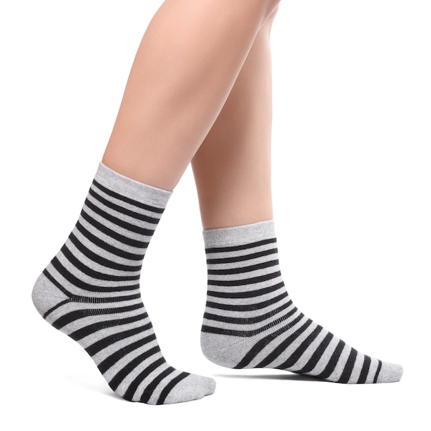 Female legs in warm striped black and grey socks isolated on white background.