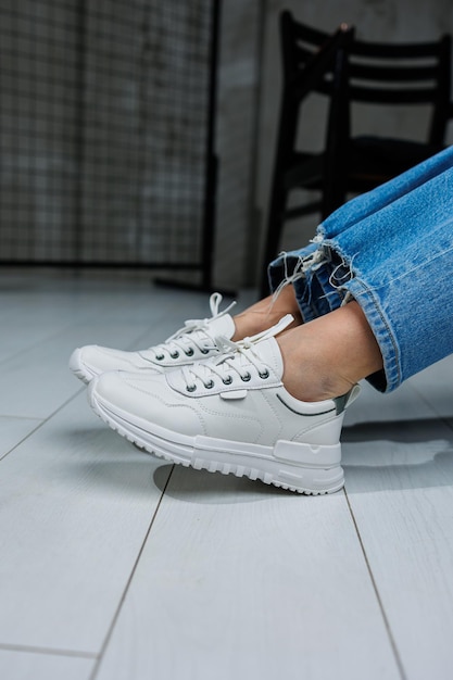 Female legs in white stylish sneakers Casual women's fashion Comfortable shoes for women Women's comfortable summer shoes