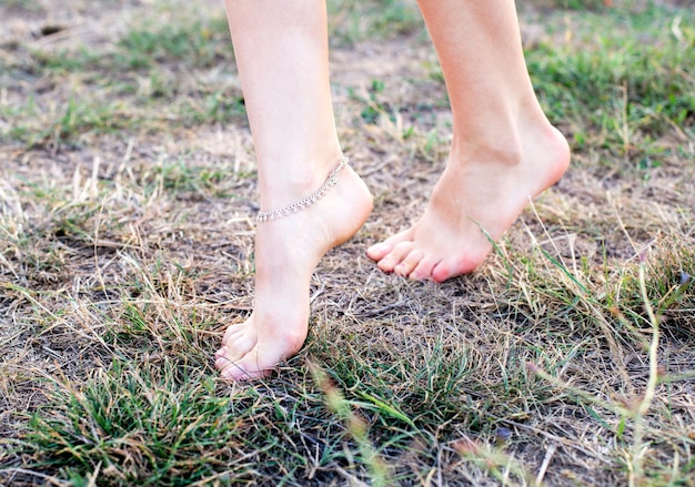 美しい装飾の背景を持つ牧草地で靴のない女性の足