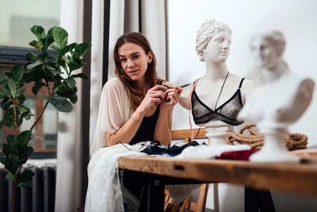 Female lingerie designer sits in her workshop.