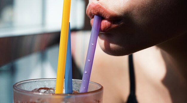 Foto labbra femminili che bevono cocktail alcolici nel bar