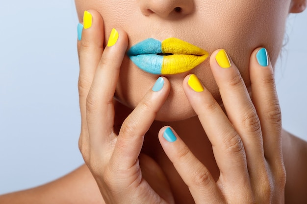 Female lips with two different lipsticks and colorful nails