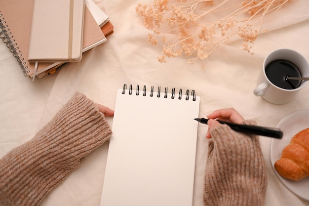 Female listing a to do lists on her spiral notepad at her minimal workspace empty spiral notepad