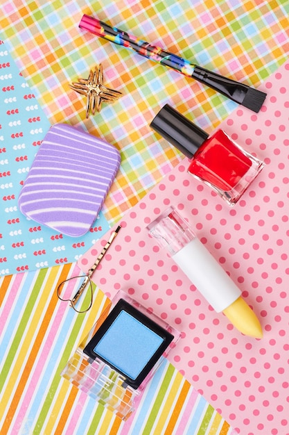 Female makeup accessories, top view. Decorative cosmetics products and jewelry on colorful background. Woman beauty items.