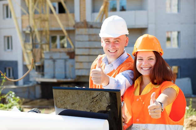 Female and male construction workers looking at laptop and smiling