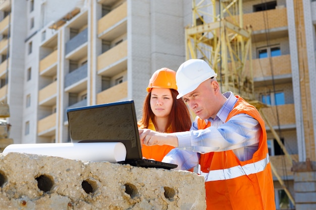 Female and male construction workers looking at laptop