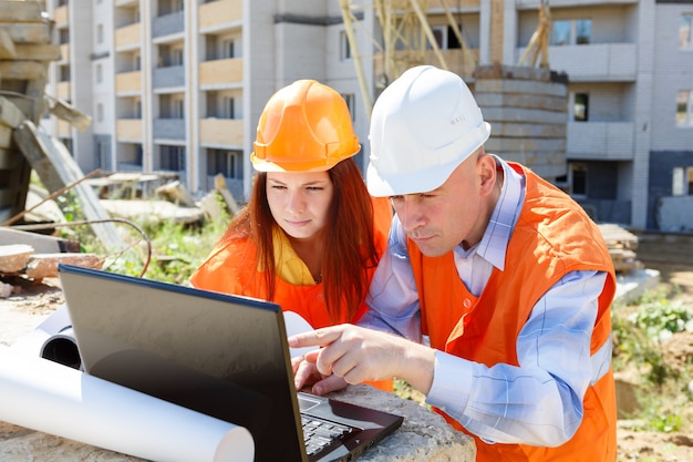 Photo female and male construction workers looking at laptop