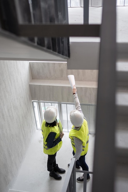 Foto ingegneri di sesso femminile e maschile con caschi e giubbotti bianchi presso gli specialisti di sicurezza antincendio del cantiere