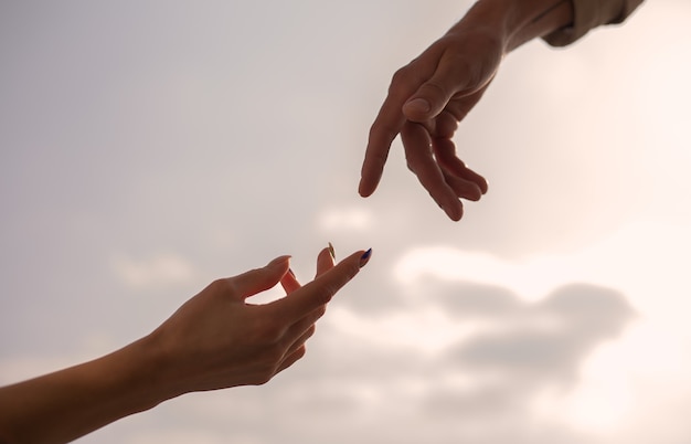 Femmina e maschio consegnano il cielo. silhouette di raggiungere, dare una mano, sperare e sostenersi a vicenda