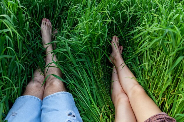 Foto le gambe del maschio e della femmina giacciono sull'erba.