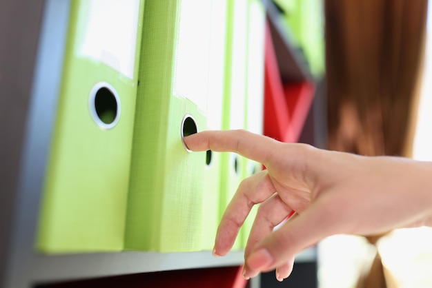 Female manager takes one folder with documents from shelf in the office closeup office shelves