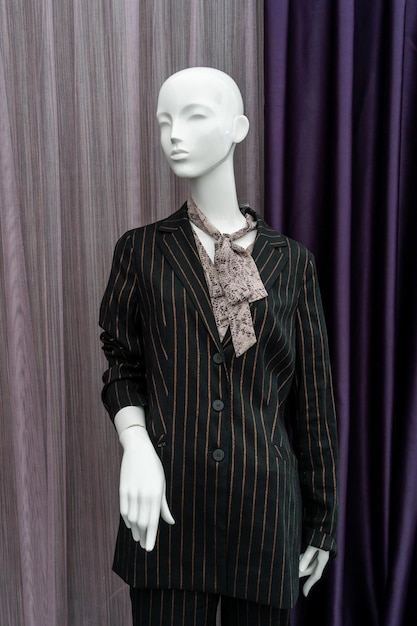 A female mannequin in a suit on a shop window sale of modern\
fashionable clothes bright youth clothing wholesale and retail