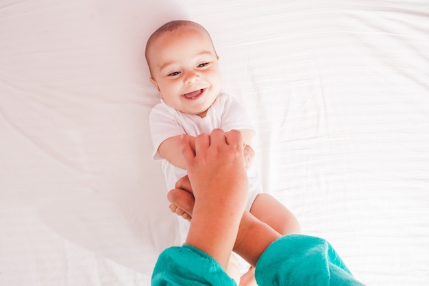 Female massaging infant hands, cute kid laughing