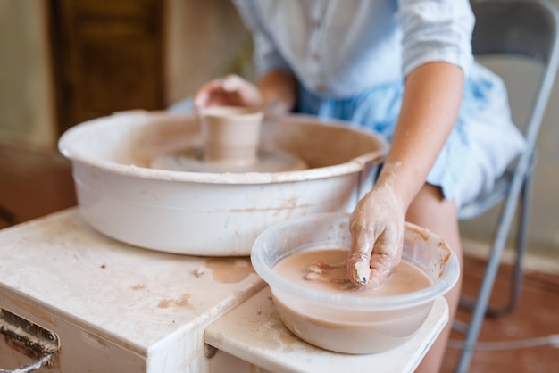 Female master making a pot on pottery wheel. Woman molding a bowl.