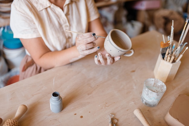 女性のマスターが鉢、陶器の工房を描きます。