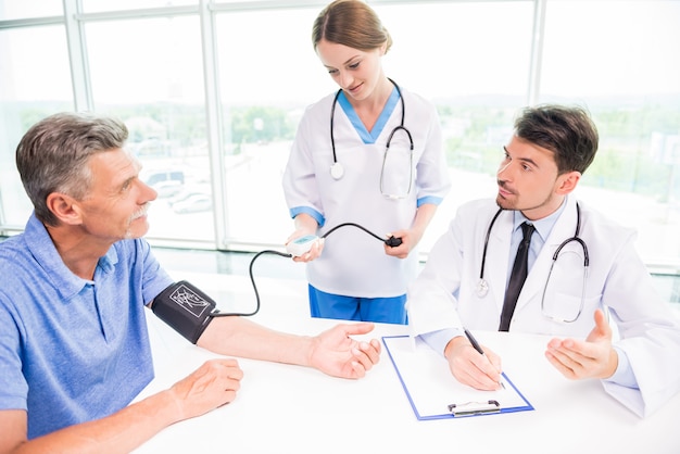 Female medical doctor taking mature patient blood pressure.