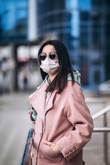 Девушки в медицинской маске на открытом воздухе в пустой город. Охрана здоровья и профилактика вирусных эпидемий, коронавирус, COVID-19, эпидемия, пандемия, инфекционные заболевания, концепция карантина.