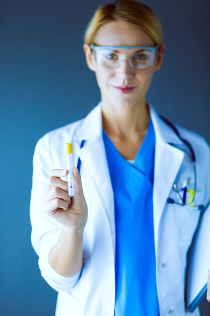 Female medical or research scientist or doctor using looking at a test tube of clear solution in a lab or laboratory